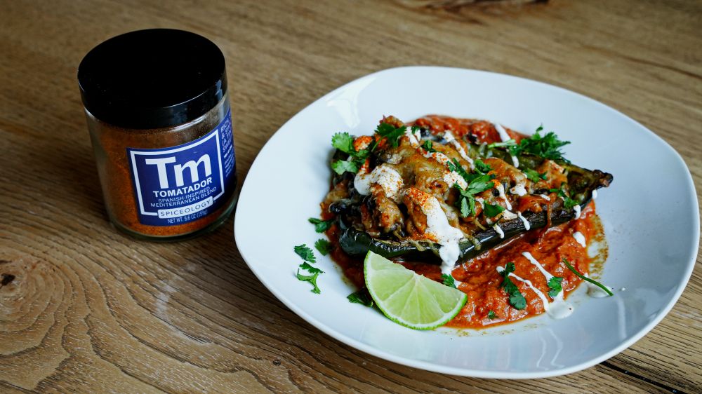 Plated Ground Turkey-Stuffed Roasted Poblano Peppers next to a jar of Spiceology Tomatador seasoning